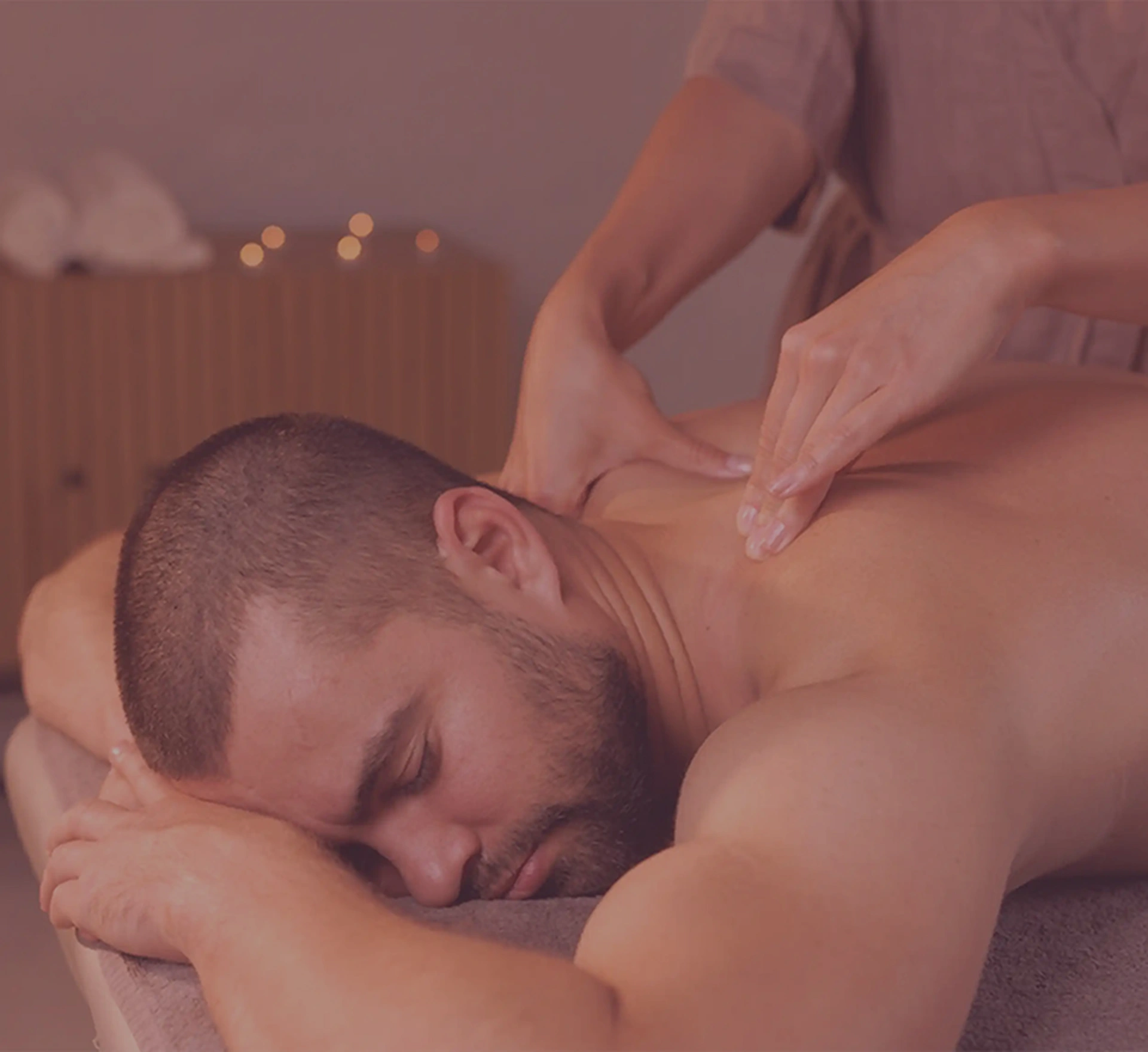 a man lying down on a massage table and getting massage from healer